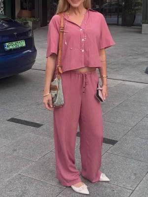 Rosa loungewear-set från Zara med vida byxor. Stl M - Säljer ett rosa loungewear-set från Zara med kortärmad, lös skjorta och matchande vida byxor med dragsko i midjan. Setet är gjort i ett mjukt, plisserat tyg som känns luftigt och bekvämt. Perfekt för en avslappnad och trendig look. Färgen är i verkligheten som de bilder när jag har setet på mig och inte som de sista två bilderna då ljuset föll konstigt. Material viskos och polyester. 