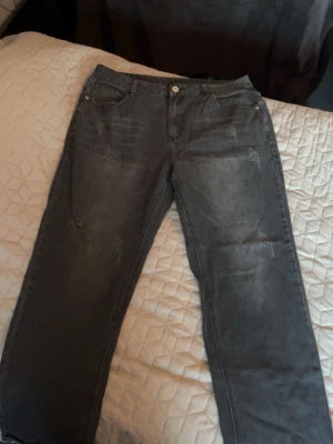 Gråa raka jeans med slitningar - Snygga grå jeans med raka ben och diskreta slitningar framtill. Klassisk femficksmodell med dragkedjegylf och knapp. Jeansen har en tvättad look och passar perfekt till en avslappnad stil.