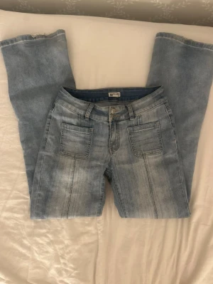 Low waist bootcut jeans  - Säljer ett par ljusblå jeans från Madlady som är bootcut och två stora fickor framtill. Jeansen har låg midja. Perfekta för en avslappnad och trendig look. Pris går att diskutera vid snabb affär!