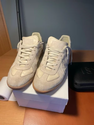 Beige sneakers i mocka och läder - Snygga beige sneakers med ovandel i mocka och läderdetaljer. Skorna har klassisk låg profil, vita snören och gummisula. Perfekta för en clean och stilren look. Passar till både jeans och shorts.