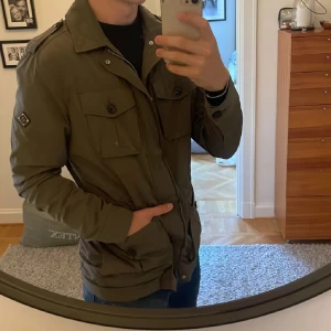 J.Lindeberg fieldjacket - Fieldjacket frän J.Lindeberg. Mörkgrön i fint skick. Jag ar 182 och väger 75kg. Storlek är M men passar också L. Originalpris är 4000. Perfekt nu till hösten. 