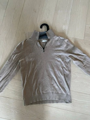 Beige halvzip-tröja från MNG - Snygg beige tröja från MNG med halv dragkedja och hög krage. Tröjan har långa ärmar och ribbade muddar vid ärmslut och nederkant. Sitter riktigt bra