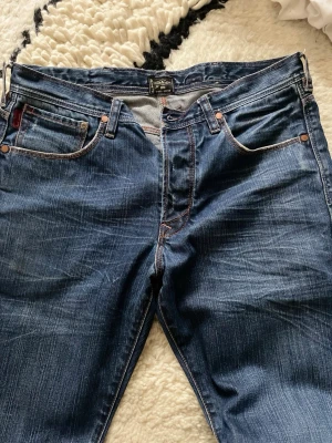 Mörkblå jeans från PSJ Paul Smith  - Snygga mörkblå jeans från PSJ med klassisk femficksdesign och kontrastsömmar. Jeansen har en rak passform och är tillverkade i slitstark denim med lätt tvättad look. Perfekta för en avslappnad och trendig stil.