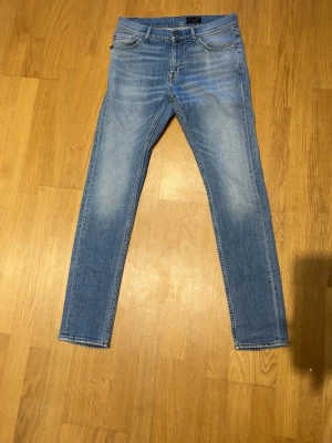 Tiger of sweden jeans  - W30 L 34. Midja 39 Längd 104. Snygga ljusblå slim fit jeans med klassisk femficksdesign och diskreta slitningar på låren. Jeansen har normal midja och raka ben, perfekta till en avslappnad stil. Materialet är mjukt denim som ger en bekväm känsla hela dagen.