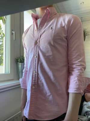 Rosa skjorta från Ralph Lauren - Säljer en rosa skjorta från Ralph Lauren. Modellen är 175 väger runt 60kg och har vanligtvis S