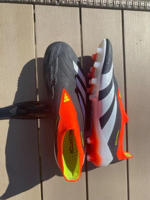 Adidas Predator fotbollsskor svart/orange - Säljer ett par Adidas Predator fotbollsskor med svart ovandel, vita detaljer och orange sock-liknande krage.