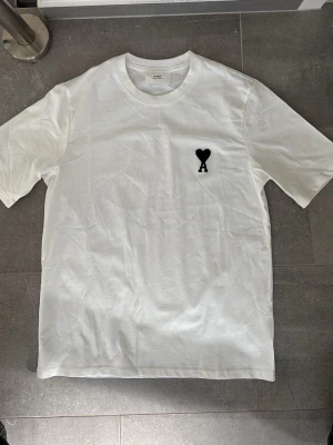Vit t-shirt från Ami Paris med hjärtdetalj - Säljer en stilren vit t-shirt från Ami Paris. Pris kan diskuteras.