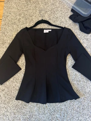 Svart topp med v-ringning Gina Tricot - Snygg svart topp från Gina Tricot med v-ringad hals. Figurnära passform som framhäver midjan och lätt utsvängd nertill. Perfekt att styla med både jeans och kjol för en trendig look. Aldrig använd, pris kan diskuteras💕
