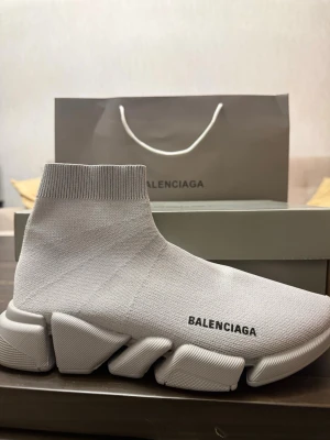 Balenciaga vit sock sneaker - Superfräsch vit sock sneaker från Balenciaga med stickad ovandel och chunky, futuristisk sula. Modellen har en tight passform som en strumpa och logga på sidan. Perfekt för dig som gillar statement sneakers och modern design.