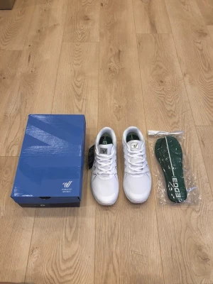 Vita sneakers från Varsity Spirit - Professionella vita cheerleadingskor från Varsity Spirit, modell Double Edge. En lätt men stabil sko som fungerar utmärkt till både gymnastik och bygg. Själv äger jag denna modell och är jättenöjd med den. Jätteskön och smidig. Vattentät yta. Storlek 39 och helt nya. Skickas nerpackat i originalkartong och extra iläggssulor följer med.