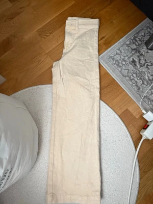 Beige raka jeans - Snygga beige jeans med rak passform och klassisk design. Byxorna har hällor för bälte och stängs med knapp och dragkedja. Perfekta för en clean och stilren look. 