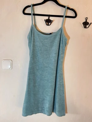 Ljusblå strandklänning - Säljer en ljusblå sommarklänning i mjukt material med smala axelband och enkel, rak passform. Perfekt för svala dagar och enkel att styla med accessoarer. Klänningen har en avslappnad look och känns riktigt bekväm. Fint skick, inga skavanker. H&M Divided, storlek M. Djur, rök och parfymfritt hem.