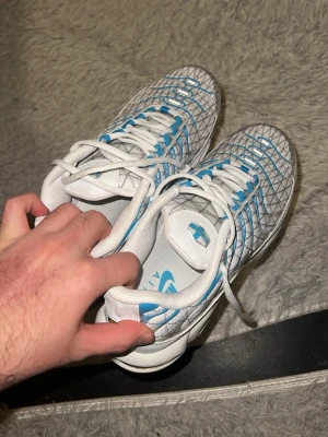Nike Air Max Plus vita/blå sneakers - Nike Air Max Plus sneakers i vitt med blå detaljer och ett unikt rutmönster på ovandelen. Skorna har klassiska vita snören, blå och gula inslag på sulan samt TN-logga på innersulan. Perfekt för dig som vill ha en cool och sportig look. pris kan diskuteras de ba skicka bud om du vill ha den som biligast så får du den för minst 500kr