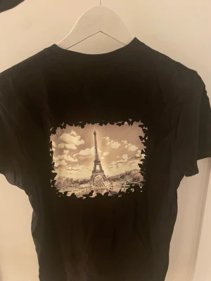 Svart t-shirt med Eiffeltornet-tryck - Svart T-shirt med Paris/ Eifelltornet motiv på ryggen! Endast 219kr! , storlek S-M finns! Vid köp ange storlek som önskas!                  Obs: helt ny, MVH MOV3