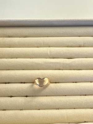 Guldfärgad hjärtformad ring - Trendig ring i guldfärg med en unik hjärtformad front. Ringen har en mjukt rundad design och glänsande yta som ger en modern och stilren look. Perfekt accessoar för dig som vill addera lite extra kärlek till din outfit.