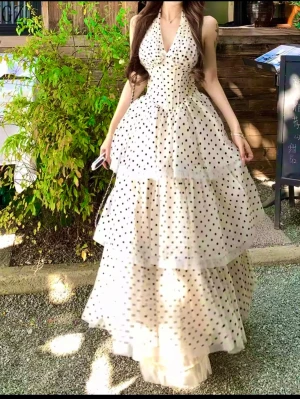 Beige Prickig långklänning med volanger - Supersöt långklänning i ljus beige med svarta prickar och flera lager volanger. Klänningen har halterneck, v-ringning och en luftig, flowy passform. Perfekt för sommarens alla tillfällen! Materialet känns lätt och svalt, troligen polyester eller liknande.