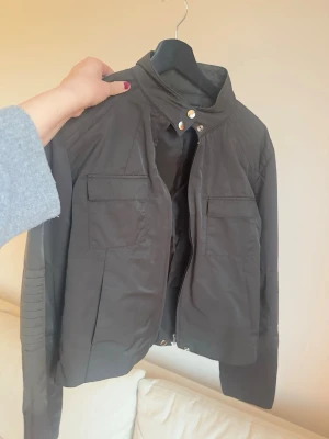 Svart vindjacka från Vero Moda - Snygg svart vindjacka från Vero Moda med krage som man knäpper. Är mer som en M men är storlek L. Har en stykgärnsfläck se bild 4