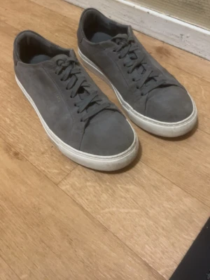 Axel Arigato skor - Snygga grå sneakers från Axel Arigato i mjuk mocka med klassisk låg profil och vita gummisulor. Skorna har matchande grå skosnören och diskret logga. Använda några gånger inga skador men gillade inte dem.
