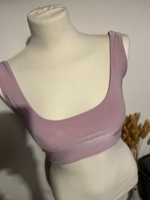 Syrenlilla crop top/ byggelös bh - En stilren ljuslila mjukt, stretchigt material med breda axelband och djup urringning. Sömlös design utan vaddering eller bygel, perfekt för en bekväm känsla hela dagen. Passar dig som gillar minimalistisk och modern stil.