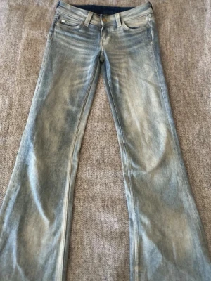 Ljusblå bootcut jeans CHEAP MONDAY - Säljer ett par ljusblå bootcut jeans från Cheap Monday med klassisk femficksmodell och coolt grafiskt märke bak i midjan. Jeansen har slitna detaljer och är tillverkade i bomullsdenim. Perfekta för dig som gillar retrovibbar och avslappnad stil. Nästan aldrig använda 