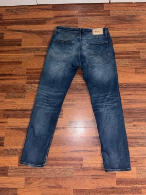 Jack & Jones regular fit jeans W32 L32 - Comfortable and stylish Jack & Jones jeans in a classic blue wash. In great condition with nice natural fading. Soft denim and a flattering regular fit that works with almost anything.  Note: the left back pocket has a small stitching defect, which actually gives the jeans a unique character (see last photo). Size W32 L32