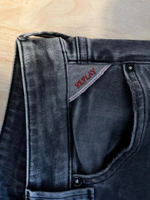 Svarta Replay jeans med raka ben - Snygga svarta jeans från Replay med raka ben och klassisk femficksmodell. Jeansen har Replay-logga i rött vid fickan och är tillverkade i mjukt denimtyg. Perfekta för en trendig och avslappnad stil.