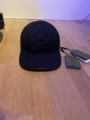Svart Gucci keps med GG-mönster - Snygg svart keps från Gucci med det klassiska GG-monogrammet över hela kepsen. Kepsen är helt ny och oanvänd. Tags är på. Pris går att diskutera såklart. 