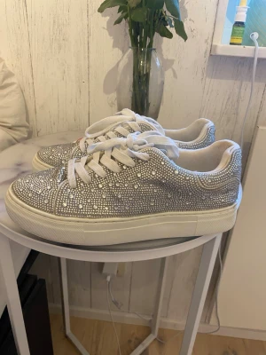 Jättefina glittriga skor från Anna Field - Jättefina glittriga skor! Älskar dem! Men tyvärr är dem lite för små för mig. Använd ett fåtal gånger på sommaren!   Det är storlek 39, lite smala för mig då jag har lite bredare fötter skulle jag säga. Så en smal 39a skulle jag säga denna sko är.   Med blotta ögat ser det ut som alla glitterkristaller sitter kvar, men det finns en svart kristall på skon vilket satt där när jag fick hem dem från affären😅. (Se sista bilden för att förstå)  Nypris: 559 kr