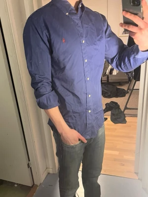 Ralph Lauren Skjorta - Tja säljer nu en Ralph Lauren Skjorta i storlek M o färgen blå. Inga tydliga defekter. Skjortan är i ett fint skick och kostar runt 1295kr nytt mitt pris är 299kr hör av dig vid frågor eller funderingar