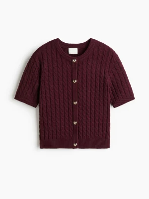 Vinröd kabelstickad kofta med kort ärm - Vinröd kabelstickad kofta med korta ärmar och rund hals. Knäpps framtill med guldiga knappar och har ribbade muddar. Nästan aldrig använd. Slutsåld hos hm. Storlek L men passar mig som är S i vanluga fall. 