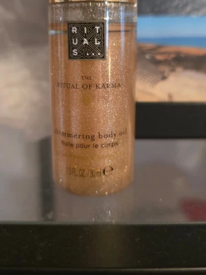 Rituals The Ritual of Karma Shimmering Body Oil - Shimmering body oil från Rituals, The Ritual of Karma. Kommer i en genomskinlig flaska med guldglittrande olja som ger huden en skimrande finish. Innehåller 30 ml och har en lyxig känsla med doft och vårdande ingredienser.