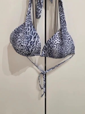Leopardmönstrad bikiniöverdel - Snygg bikiniöverdel med leopardmönster i svart och vitt. Triangelformade kupor och knytband i nacken och ryggen för justerbar passform. Perfekt för strandhäng eller poolparty.