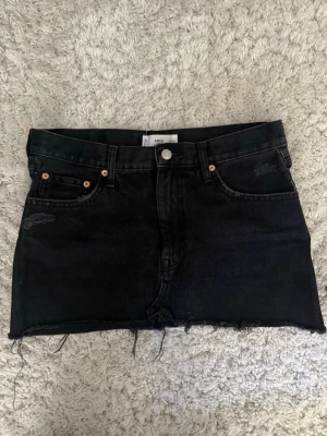 Svart minikjol från Mango - Säljer en svart kort jeanskjol från Mango som jag köpte nyligen men tyvärr passade den inte då den var lite för stor i midjan. Har egentligen str S men köpte M så har man M passar den! ❣️