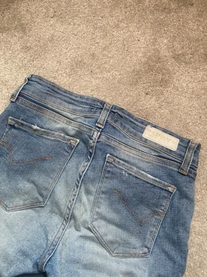 Blå skinny jeans från ONLY - Säljer ett par blå skinny jeans från ONLY med slitningar och tvättade detaljer. Jeansen har normal midja och lite tajtare passform