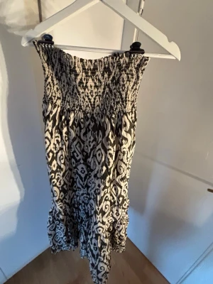 Svart brun mönstrad långkjol - Supersnygg svart brun långkjol med elastisk smock  och volang nertill. Kjolen har ett grafiskt mönster och är perfekt för varma dagar. Materialet känns lätt och luftigt❤️