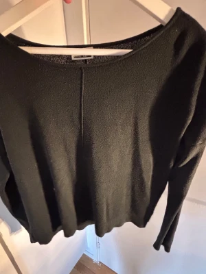 Svart stickad tröja - En stilren svart stickad tröja från Filippa K med rund halsringning och lång ärm. Tröjan har en rak passform och en dekorativ söm mitt fram och bak. Perfekt basplagg i mjukt material för en clean look.