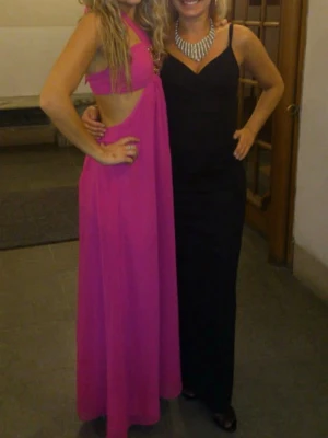 Rosa balklänning student bal fest bröllop - Säljer en snygg rosa långklänning med cut out-detaljer i sidan och ett axelbandslöst parti. Klänningen har en modern och ungdomlig design med en svepande kjol och markerad midja. Perfekt för dig som vill sticka ut på bal eller fest.