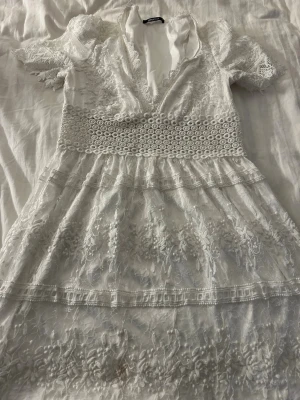 Vit spetsklänning med v-ringning - Superfin vit kortklänning med v-ringning och spetsdetaljer. Perfekt för studenten 