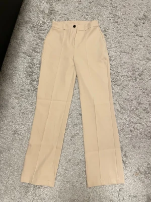 Beige kostymbyxor XS Petite – nya - Beige kostymbyxor i storlek XS Petite. Aldrig använda, helt nya skick 🤍  Sitter fett snyggt och ger en clean, classy vibe – perfekta både till vardag och lite mer uppklätt yäni. Rak modell med pressveck som ger en stilren look.  Säljer pga kommer tyvärr inte till användning. Passa på ✨