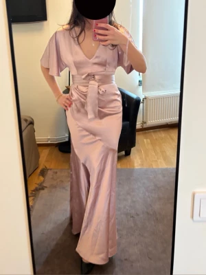 Lång satin klänning rosa - Otroligt klänning i bra satin kvalité. Storlek xs-s. Skulle säga närmare xs så lite tajt på mig. Bandet kan man ta av helt om man vill Jag är 167 lång  I princip oanvänd- inga defekter Perfekt till balen, sittningar eller fina firanden. Så lyxog