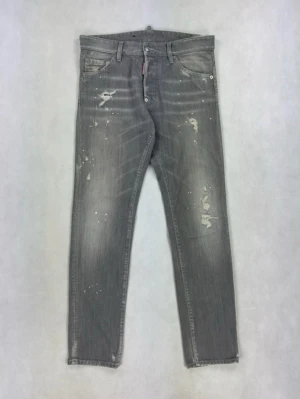 Grå distressed jeans från Dsquared2 - Säljer ett par grå jeans från Dsquared2 med slitna detaljer och färgstänk för en edgy look. Jeansen har smal passform, klassisk femficksdesign och är tillverkade i denim. Perfekta för dig som gillar streetstyle och vill sticka ut.