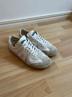 Premiata Skor - Säljer ett par stilrena Premiata sneakers i storlek 42.  Använda men fortfarande i fint skick. Skorna är rengjorda och har mycket kvar att ge.  * Storlek: 42 * Färg: Vit/offwhite med beige mockadetaljer * Material: Skinn och mocka * Skick: Bra använt skick  Perfekta till både vardag och en mer uppklädd look.  📦 Skickas snabbt. 💬 Hör gärna av dig vid frågor eller om du vill ha fler bilder.