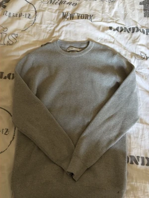 Ljusgrå stickad tröja från S.C.W - En stilren ljusgrå stickad tröja från S.C.W i återvunnet material.Ribbade muddar och är enkel att matcha med allt! Storlek passar även M