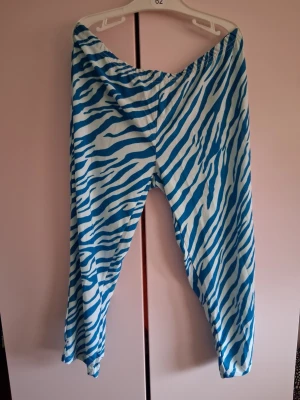 Blåvita zebramönstrade leggings - Säljer ett par 3kvarts leggings med blått och vitt zebramönster. Har aldrig blivit använda i storlek s sömmen har lossnat lite sen bild därför säljes billigt De har elastisk midja och är tillverkade i ett mjukt, stretchigt material som sitter skönt på kroppen. Perfekta för dig som vill sticka ut med ett djuriskt mönster!