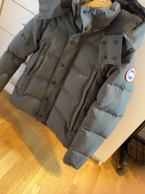  cannada goose jacka - En vinterjacka i storlek xs från cannada goose i färgen mörkgrå/grafitgrå  som inte har några  skador men  en liten linje me något som jag inte vet vad det är
