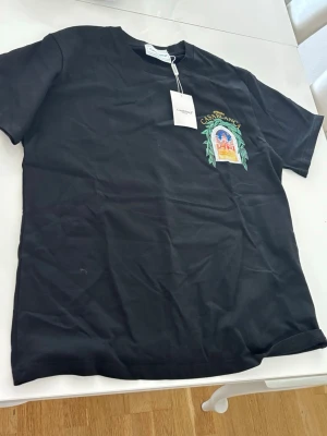 Svart t-shirt - Svart t-shirt med tryck på bröstet och ryggen. Klassisk passform och rund hals. Perfekt för dig som vill ha en unik och stilren tee med cool grafik.