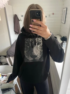 The cool elephant hoodie - Säljer en svart the cool elephant hoodie med stor huva och ett leopardtryck i svartvitt på bröstet. Trycket med loggan på ryggen är lite slitet, samt en lapp inuti. 