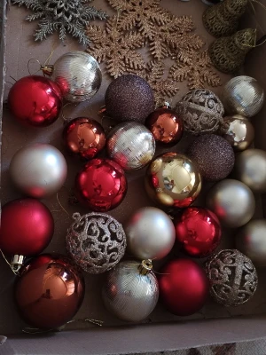 Blandade julgranskulor och dekorationer - En samling julgranskulor i rött, guld, silver och brons samt glittriga snöflingor och bollar med mönster. Kulorna är både blanka och matta, vissa med räfflad yta och andra med glitter. Perfekt för att pynta granen eller skapa julstämning hemma.