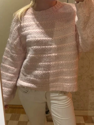 Ljusrosa fluffig stickad tröja - Supermjuk och fluffig stickad tröja i ljusrosa med breda ränder i strukturen. Tröjan har rund halsringning och långa ärmar, perfekt för att hålla sig varm under sommarkvällar🧘🏼‍♀️💗