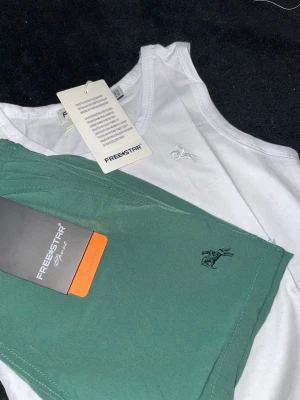 Freestar linne och boxers för barn - Snyggt set från Freestar med ett vitt linne och gröna boxershorts. Båda plaggen har en liten broderad logga. 100% Cotton. Set finns olika storlekar.